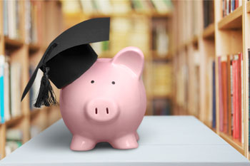 Vor Bücherregalen steht ein rosafarbenes Sparschwein mit Doktorhut.